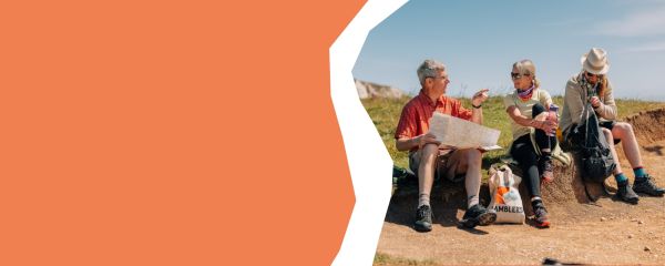 3 walkers sit and rest on a coastal path walk in the sunshine